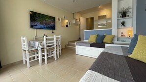 Ein modernes Schlafzimmer mit Bett, Schreibtisch und Stuhl. An der Wand hängt ein Gemälde und ein Regal zeigt Dekorationsobjekte.