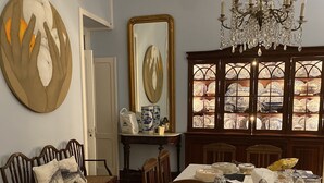 A dining room with a table set for four, surrounded by wooden chairs. A chandelier hangs above the table, and a large mirror is mounted on the wall. - House of Saint Margaret (Ponta Delgada)