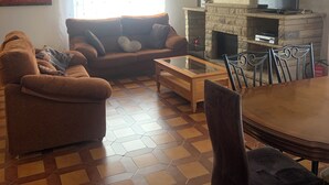 Un salon avec un canapé, une table basse, un téléviseur et une cheminée.