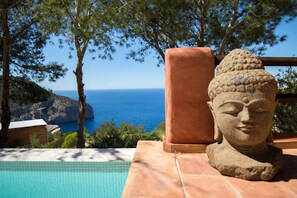 Una estatua de Buda de piedra junto a una piscina con vistas al mar.