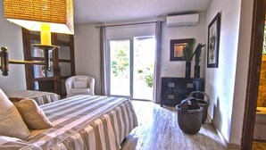 A bedroom with a bed, a chair, a desk, a lamp, and a window.