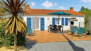 Une maison avec un toit en tuiles, une terrasse avec des meubles d’extérieur et un espace barbecue.