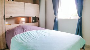 Une chambre à coucher avec un lit, une tête de lit en bois, une table de chevet, une lampe et une fenêtre avec des rideaux.