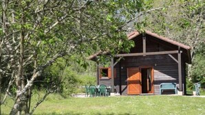 Une cabane rustique avec une façade en bois, une véranda avec des chaises et une petite table.
