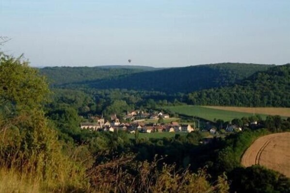 A rural village with houses clustered together, surrounded by lush green hills and fields.