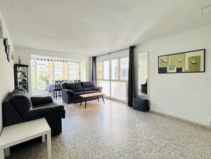 Un salon moderne comprenant un canapé, une table basse et un coin repas avec des chaises.