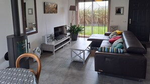 Een moderne woonkamer met een open haard, een bank, een televisie en een groot raam met gordijnen.