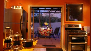 Una cocina con refrigerador, estufa y mesa de comedor con sillas.