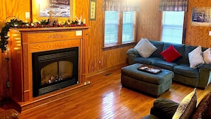 A cozy living room with a fireplace, wooden walls, a sofa, and a coffee table.