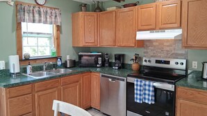 A kitchen with wooden cabinets, a stainless steel dishwasher, a microwave, a coffee maker, and a stove.