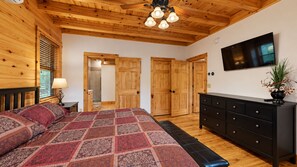 A bedroom with a bed, a dresser, a TV, and wooden doors. - Grand Ebs View Lodge, Luxury Log Home, Views, Hot Tub, Sauna, EV Charge, 3D Tour (Jay)