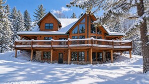 A large wooden cabin with a balcony, surrounded by snow-covered trees. - Grand Ebs View Lodge, Luxury Log Home, Views, Hot Tub, Sauna, EV Charge, 3D Tour (Jay)