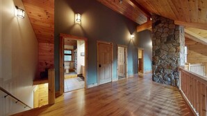Un intérieur spacieux avec des planchers en bois, un mur d’accent en pierre et de nombreuses portes donnant sur d’autres pièces.