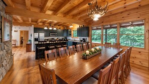 A spacious wooden interior with a large dining table, kitchen area, and large windows offering a view of the outdoors. - Grand Ebs View Lodge, Luxury Log Home, Views, Hot Tub, Sauna, EV Charge, 3D Tour (Jay)
