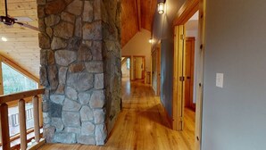 Un intérieur en bois avec un pilier en pierre, un plancher en bois et une balustrade en bois.