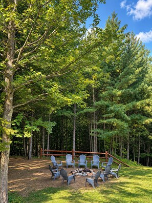 An outdoor seating area with chairs arranged around a fire pit, surrounded by a forested landscape. - Grand Ebs View Lodge, Luxury Log Home, Views, Hot Tub, Sauna, EV Charge, 3D Tour (Jay)