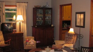 A cozy living room with a television, two lamps, a cabinet with glass doors, and a framed picture on the wall.
