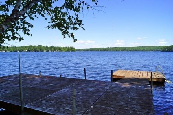 Guests can enjoy a serene lakeside experience from this dock, surrounded by a forested shoreline.