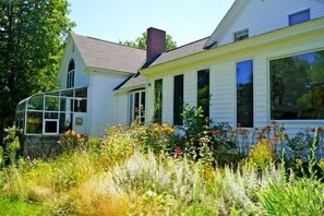 Stunning two-story house with a gabled roof and brick chimney, surrounded by a beautifully maintained garden.