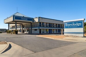 A Travelodge hotel with a two-story structure, a covered parking area, and a clear blue sky. - Travelodge by Wyndham Albuquerque West (Albuquerque)