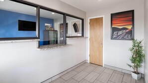 Een moderne hal met een blauwe accentmuur, een houten deur, een lijst met afbeelding en een potplant.