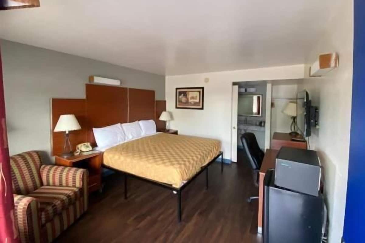 Une chambre d’hôtel équipée d’un lit, d’un bureau, d’une chaise, d’une télévision et d’un petit réfrigérateur.