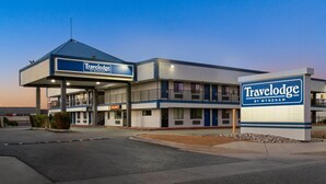 Een Travelodge by Wyndham hotel met een gebouw uit twee verdiepingen, een overdekte entree en een zichtbaar ‘Beschikbaar’-bord.