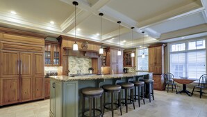 A spacious kitchen with a large island, bar stools, and a dining area with a table and chairs. - GORGEOUS 7 Bedroom 2nd Row Ocean Home with Private Pool & Game Room (Hilton Head Island)