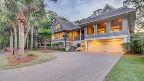 A two-story house with a driveway, a garage, and a well-maintained lawn. - GORGEOUS 7 Bedroom 2nd Row Ocean Home with Private Pool & Game Room (Hilton Head Island)