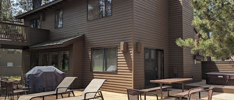 Een tweelaags huis met een terras, inclusief buitenmeubilair en een overdekte barbecueplaats.