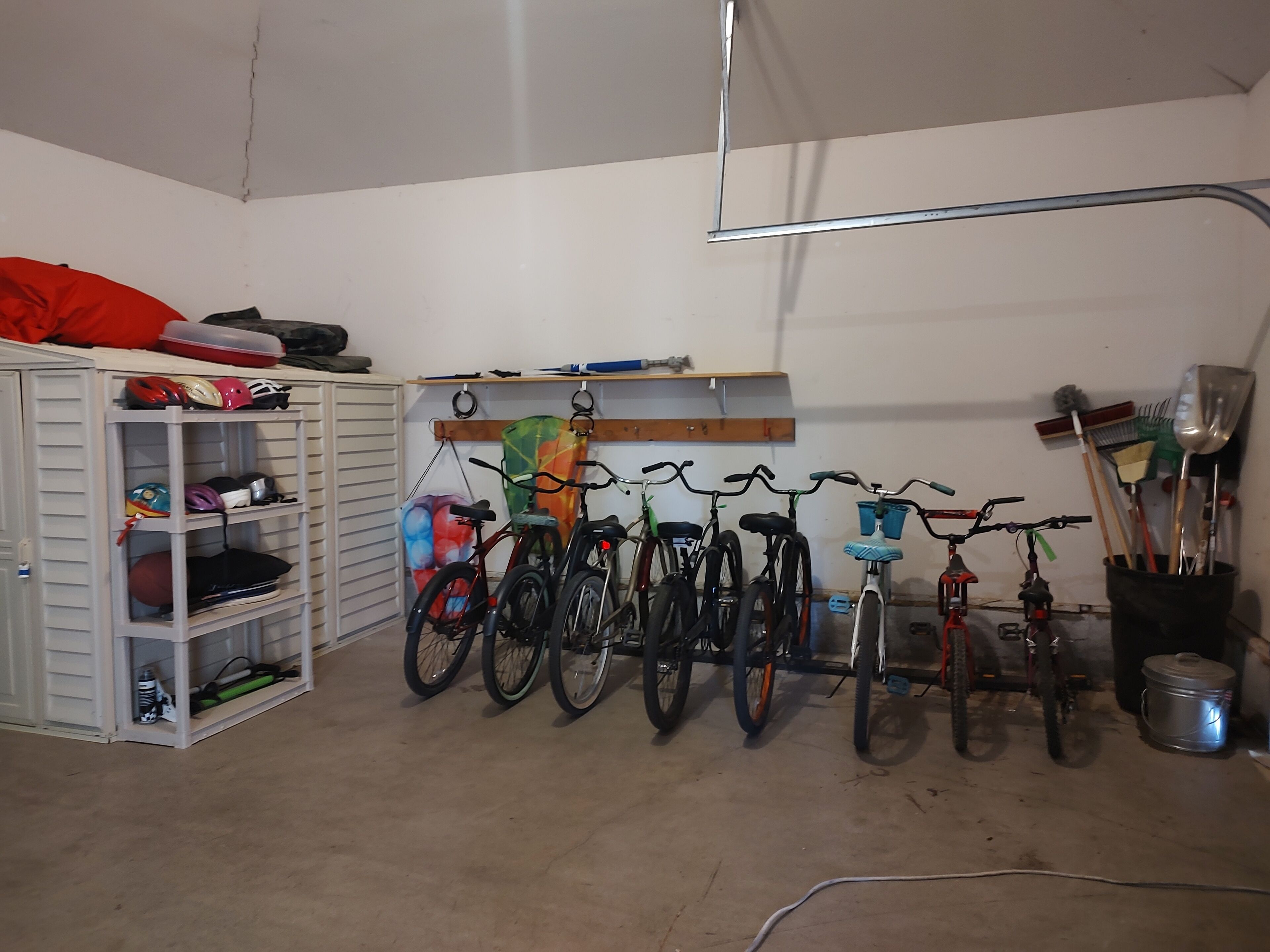 A garage with bicycles, helmets, and sports equipment.