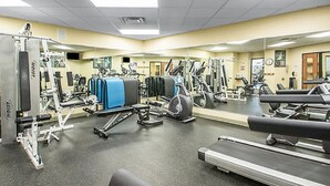 A gym with various exercise machines, a mirrored wall, and a treadmill.