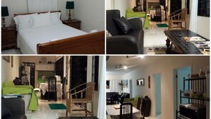 A hotel room with a wooden bed, a bedside table with a lamp, and a view of the dining area. - Ridge Bay Chateau (Port Antonio)