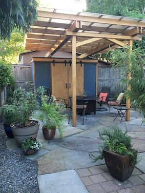 Relax in a serene outdoor space with a pergola, seating area, and lush greenery.