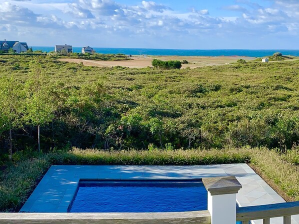 Una piscina amb vistes a l'oceà i un paisatge amb gespa.