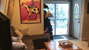 A cozy living room with a dark brown sofa, a wooden coffee table, and a cowhide rug. A large poster of a man on a Pinto pony is on the wall. - Cabin in Breckenridge  - Walk to Main Street & Peak 9 Lifts (Breckenridge)