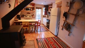 A kitchen with wooden cabinets, a microwave, a stove, and a refrigerator. There is a dining table with chairs and a rug on the floor. - Cabin in Breckenridge  - Walk to Main Street & Peak 9 Lifts (Breckenridge)