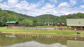 A lakeside view with a wooden cabin, a barn, and a fenced area. - BEAUTIFUL SMOKY MOUNTAINS
Peaceful and Secluded Peace of Heaven Cabin (Sevierville)