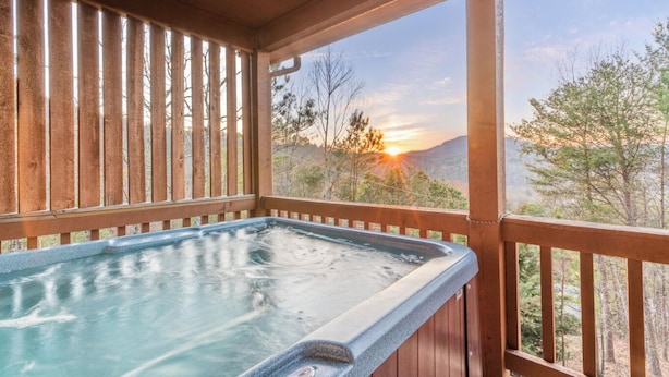 A hot tub in a wooden deck with a view of a sunset over mountains. - BEAUTIFUL SMOKY MOUNTAINS
Peaceful and Secluded Peace of Heaven Cabin (Sevierville)