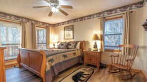 A bedroom with a wooden bed, a nightstand, a chair, a ceiling fan, and a window with blinds. - BEAUTIFUL SMOKY MOUNTAINS
Peaceful and Secluded Peace of Heaven Cabin (Sevierville)