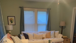 Een woonkamer met een bank, een bijzettafeltje en een plafondventilator.