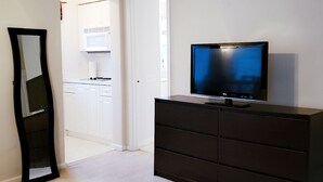 Una habitación con un aparador oscuro, un televisor de pantalla plana y un espejo.