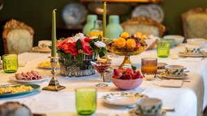 Uma mesa de jantar posta com diversos pratos, copos e um vaso de flores.