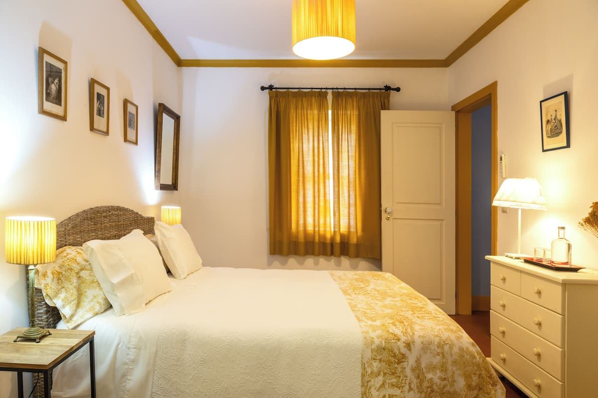 A bedroom with a bed, bedside lamps, a dresser, and a door.