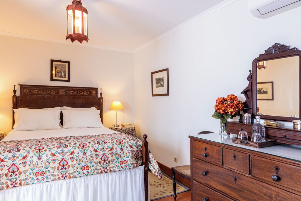 A hotel room with a bed, bedside lamps, a dresser, a mirror, and a wall-mounted picture.