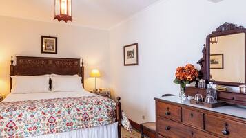 A hotel room with a bed, bedside lamps, a dresser, a mirror, and a wall-mounted picture.