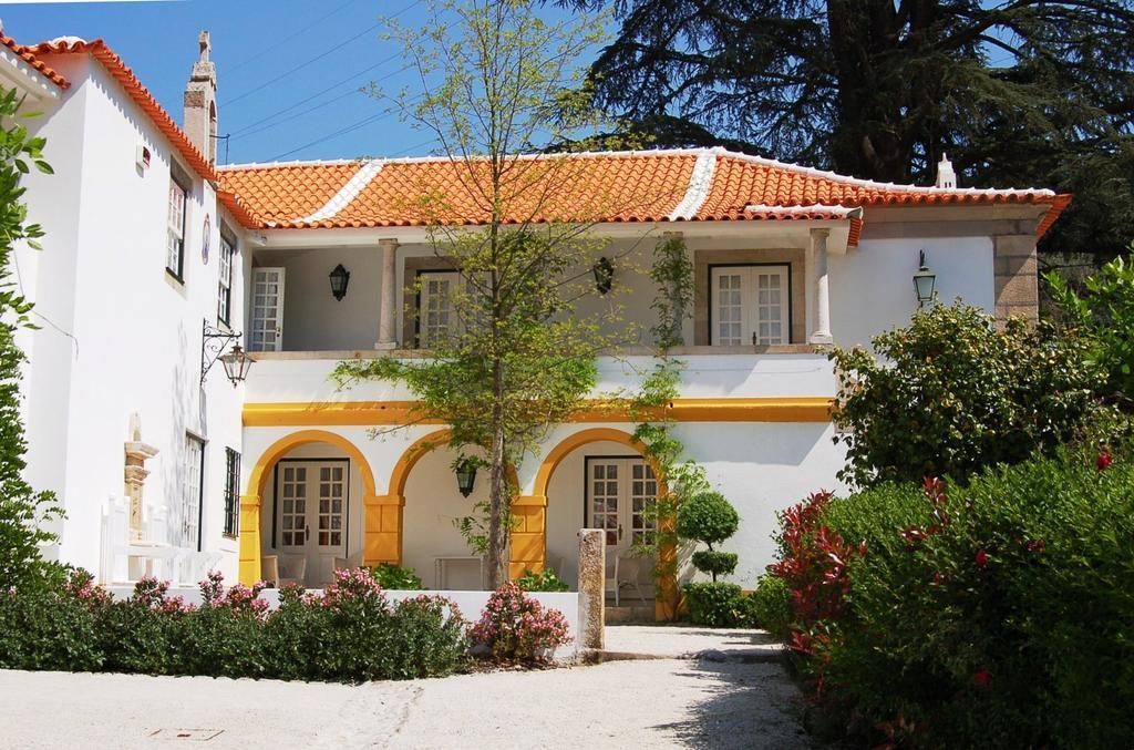 A two-story building with a tiled roof, arched windows, and a white facade with yellow trim.