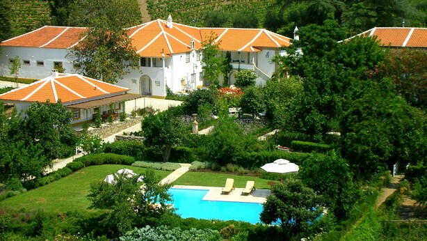 Uma grande propriedade com vários edifícios, piscina e vegetação exuberante.