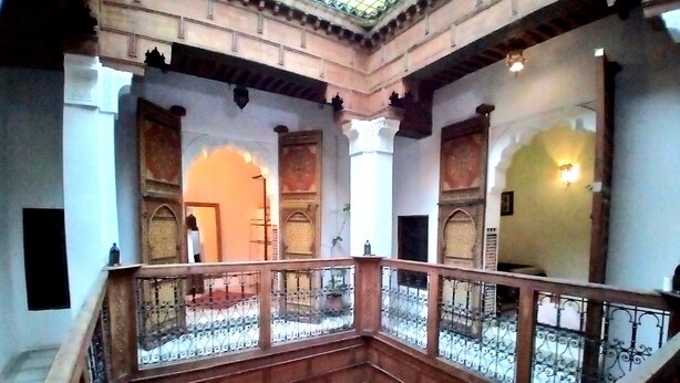 Ein mehrgeschossiges Interieur mit Balkon, verzierten Bögen und einer Treppe.