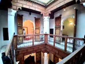 Interior de diversos nivells amb un balcó, arcs ornamentals i una escala.